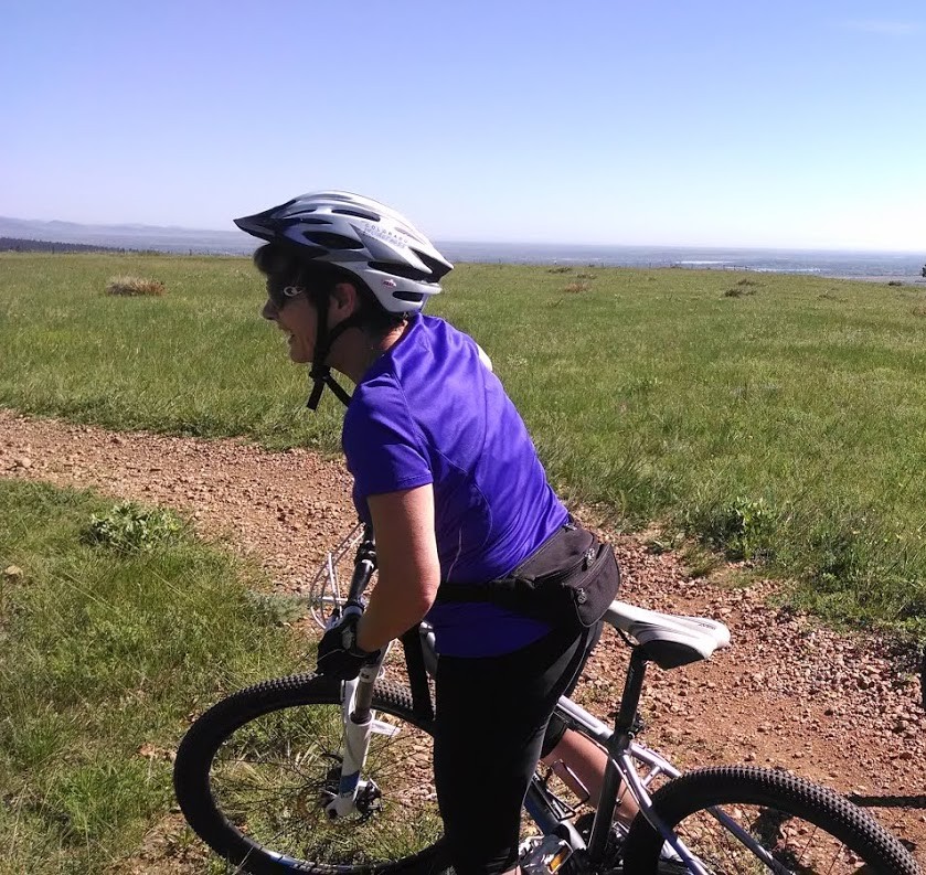Patrice mountain biking on a grassy ridge trail